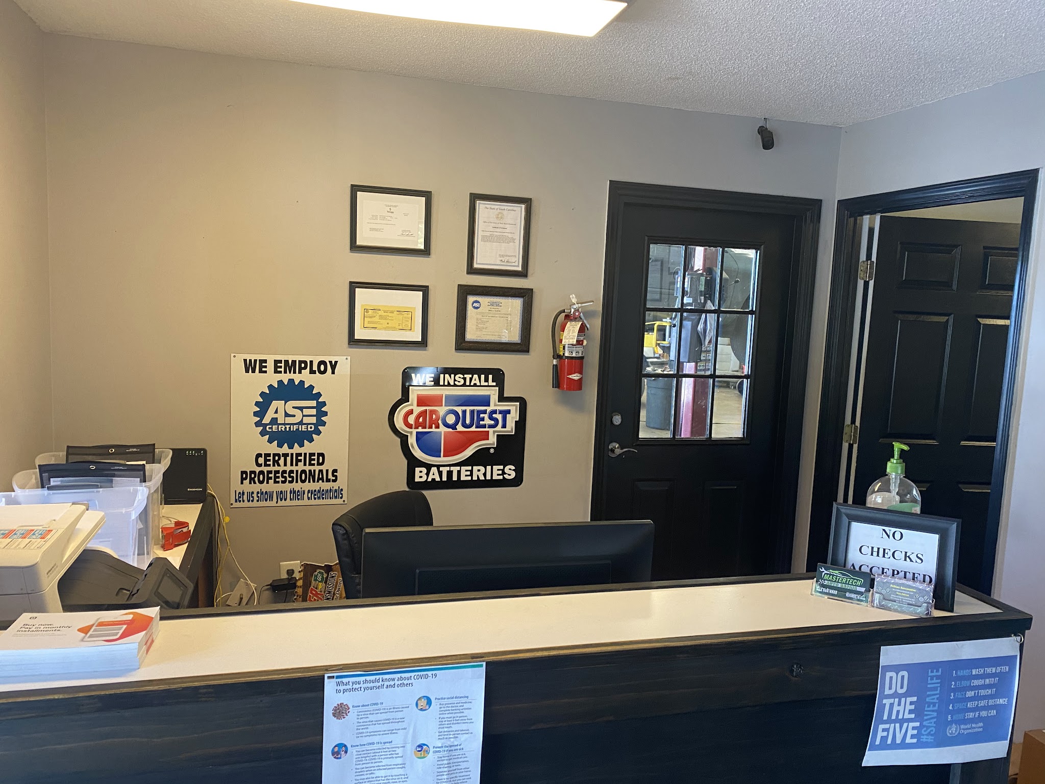 Front desk with ASE certified and CARQUEST battery signs and framed certificates