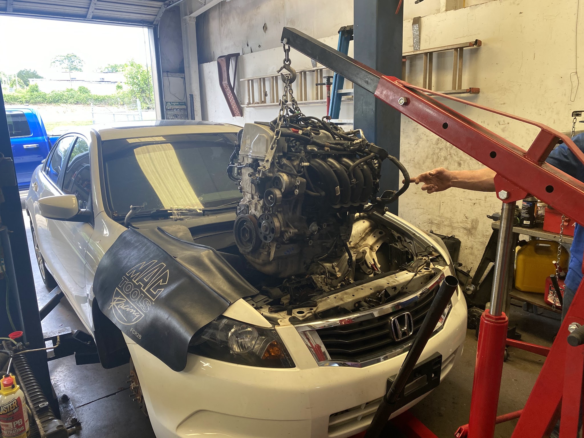 An engine lifted out of a Honda on the shop's hoist