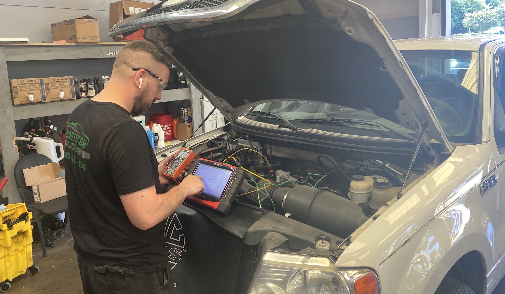 A technician running a diagnostic scan under the hood of an SUV