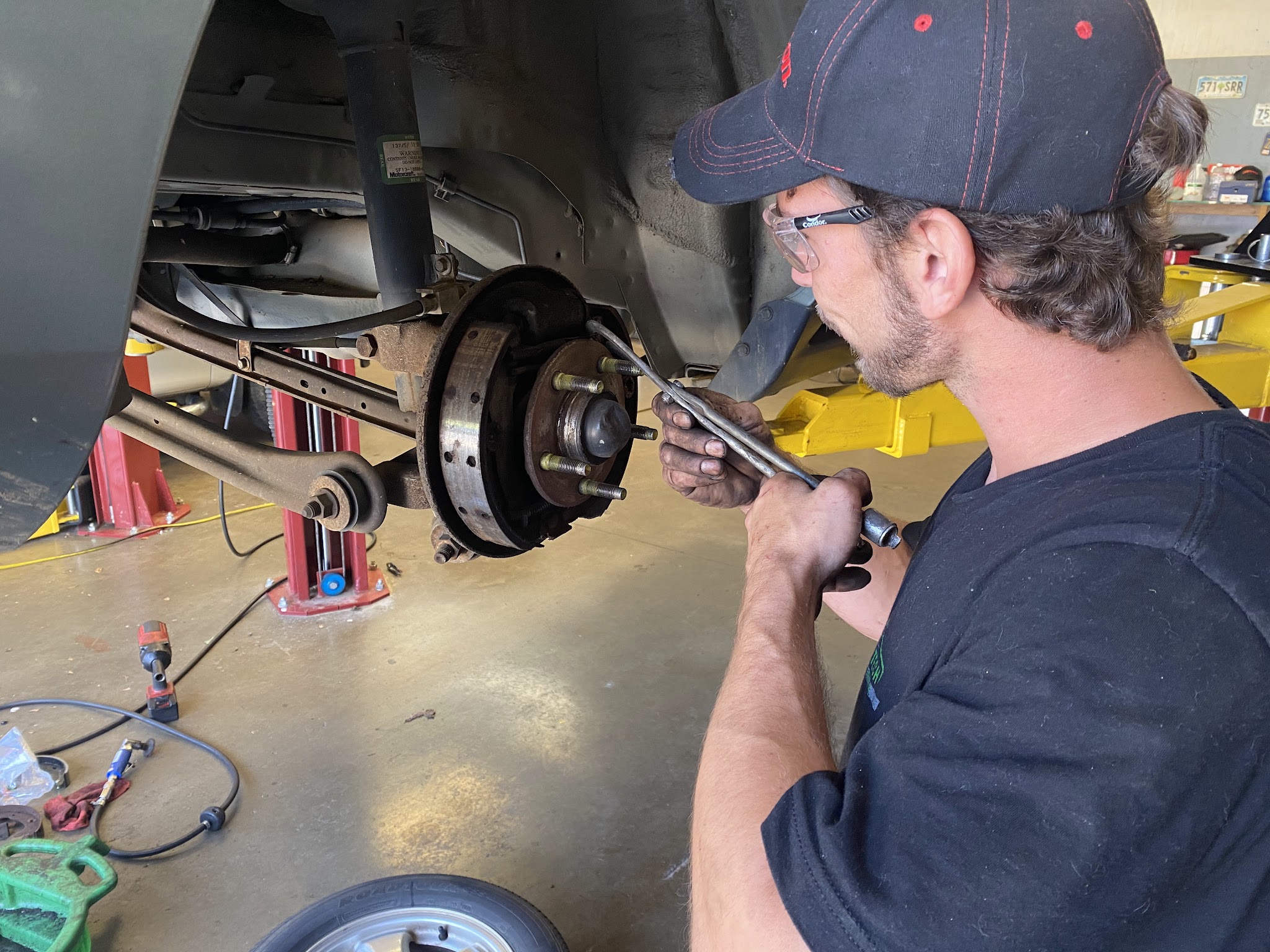 A technician working on a wheel and brake assembly on the lift