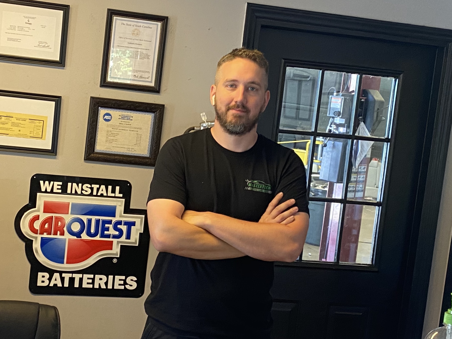 A MasterTech technician standing by the CARQUEST batteries sign